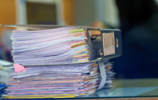 IMR Digital stack of papers in a binder with colorful tabs signifying back file scanning