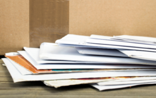 A stack of business mail on a desk signifying the importance of mailroom services for busy offices.
