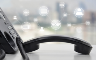 Close up of a business phone system with icons of VoIP communication services hovering above.