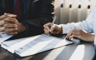 Close-up of two business professionals at a desk reviewing and signing a contract, representing a printer lease agreement in a corporate setting.