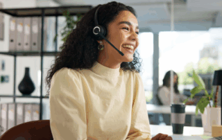 A smiling, happy customer service representative speaks on a headset in a modern office signifying copier service.