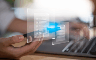 Conceptual image for intelligent data capture solutions - a close up of a worker on a laptop with icons of files overlaid.