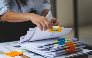 Close up of an office employee sifting through a stack of collated documents signifying the need for some businesses to invest in a production printer.