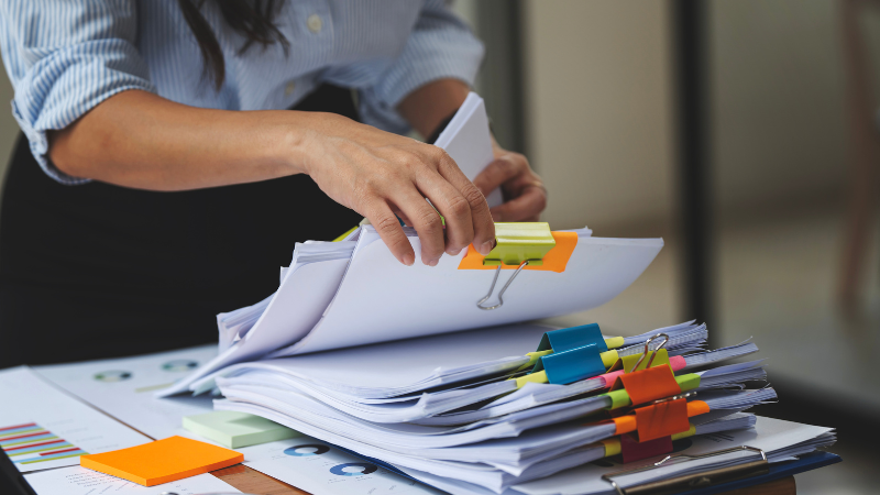 Close up of an office employee sifting through a stack of collated documents signifying the need for some businesses to invest in a production printer.