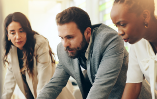 Business professionals collaborating around connected technology systems and workflows in a modern office environment.