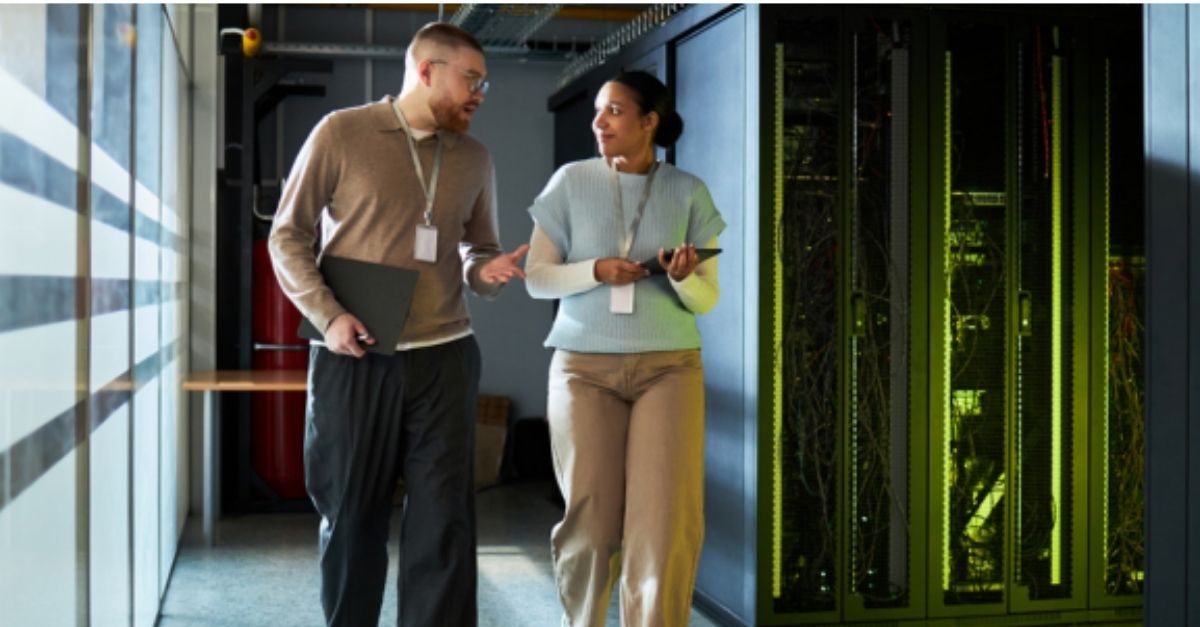 Two business professionals walking through a server room discussing IT infrastructure, backup, and recovery systems