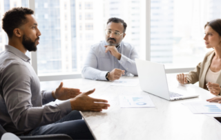 Business leaders meeting with an IT consultant to discuss managed IT services and technology strategy.