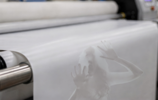 Translucent ghostly figure appearing on paper moving through a commercial printing press.